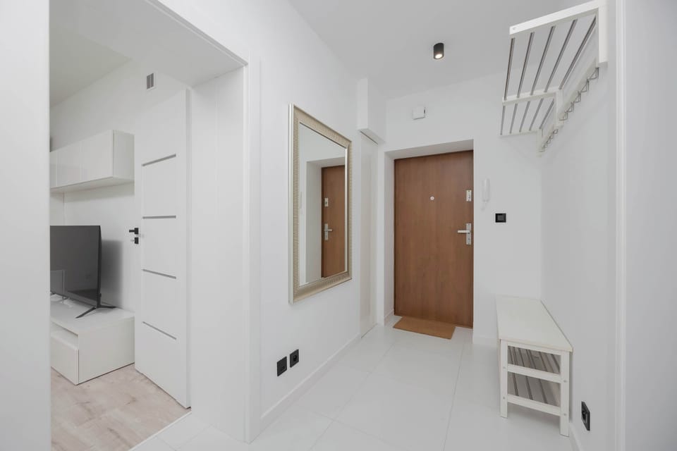 A clean and functional hallway with a shoe rack, a coat rack, and modern lighting.