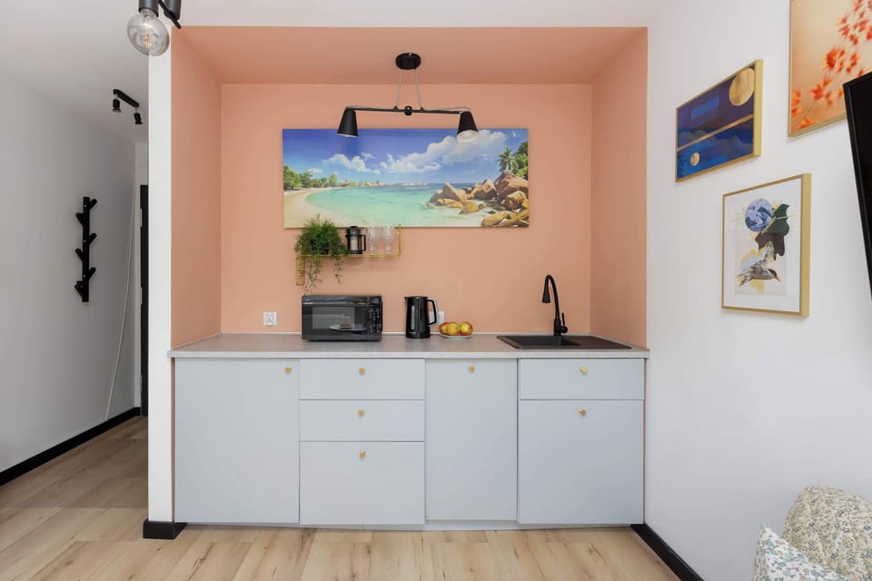 Functional kitchenette with bright furniture and appliances.