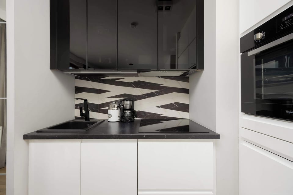 A compact, fully equipped kitchen with a black-and-white backsplash.