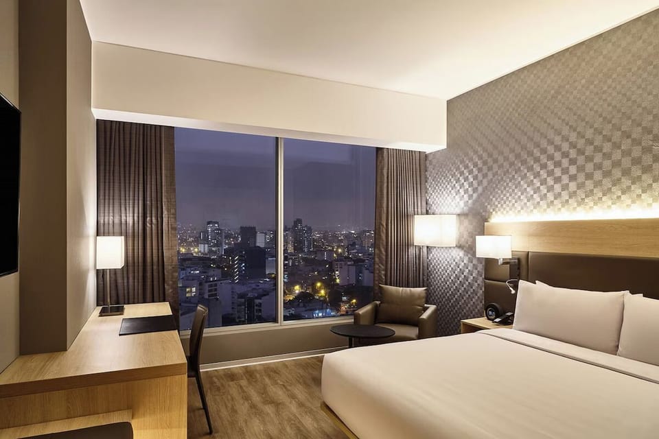 Unwind in crisp bedding with dazzling city lights outside.