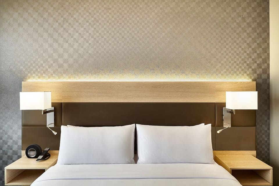 Sink into pillowy comfort beneath warm, ambient headboard lighting.