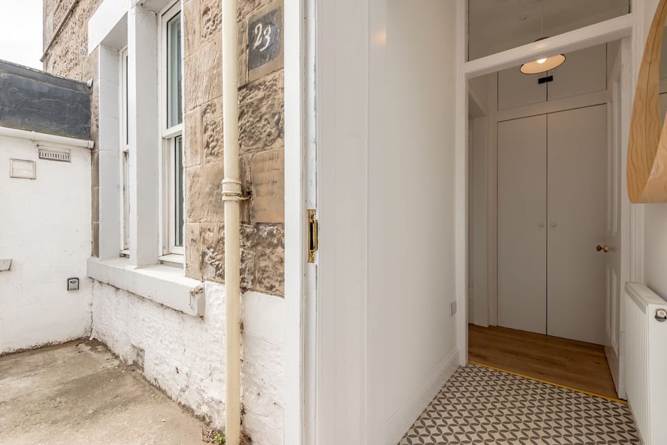 Exterior view of stone building with white entrance to ground floor flat.