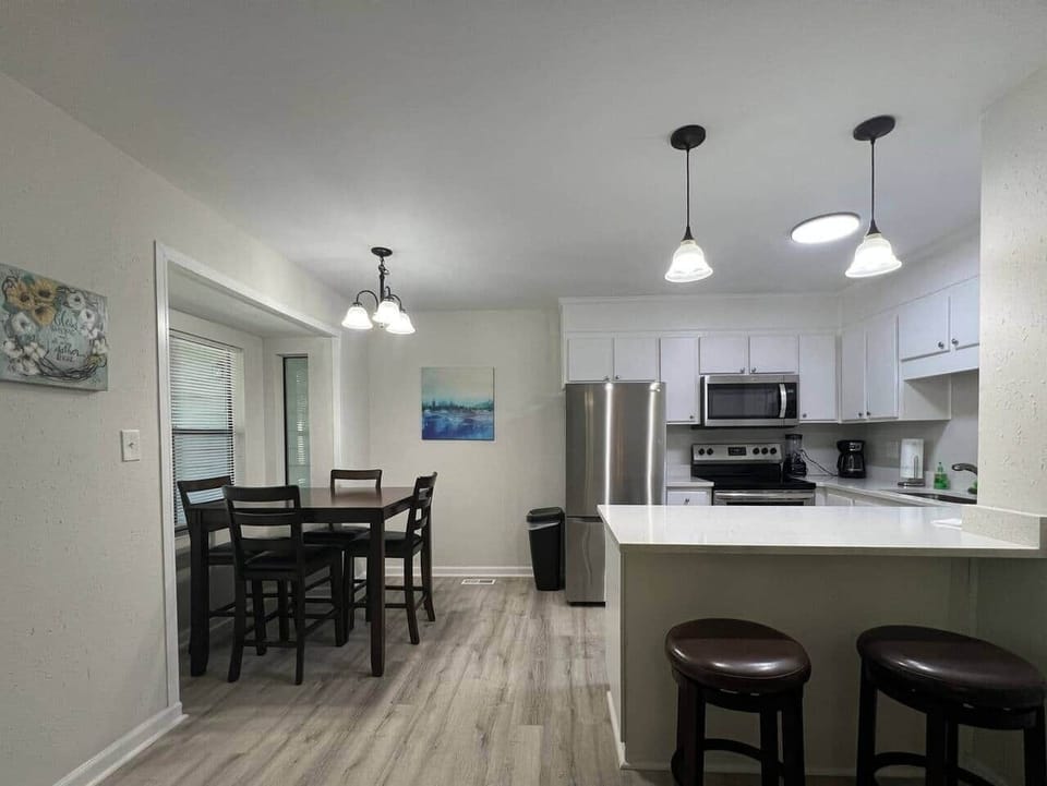 This fully equipped kitchen features stainless steel appliances, a large counter with seating, and a cozy dining nook framed by natural light. Whether you’re cooking a full meal or enjoying takeout, this space is perfect for gathering and dining in.