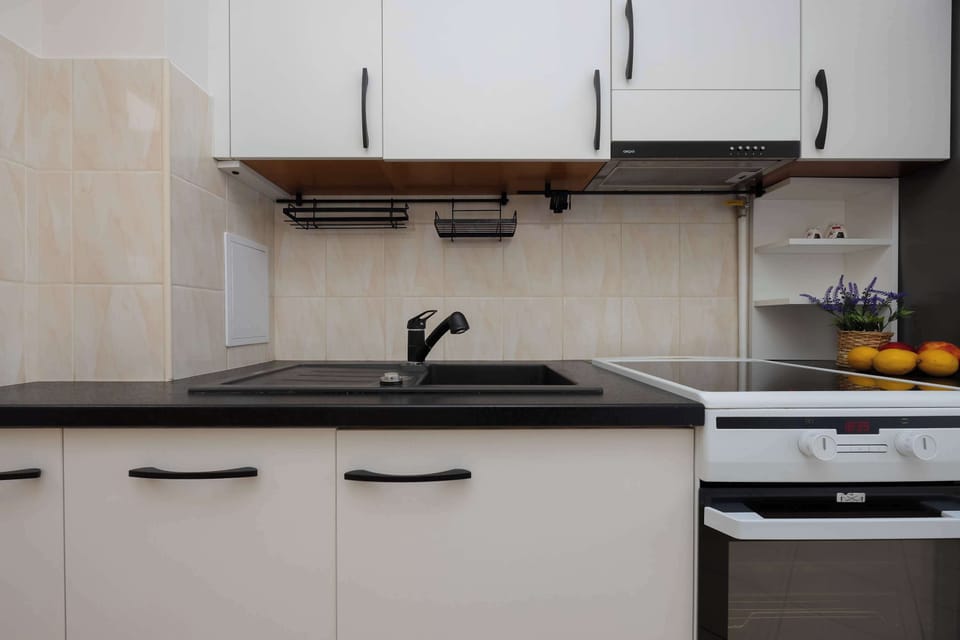 A kitchen with modern white and black cabinets, a stove, and a backsplash, creating a clean and stylish design.