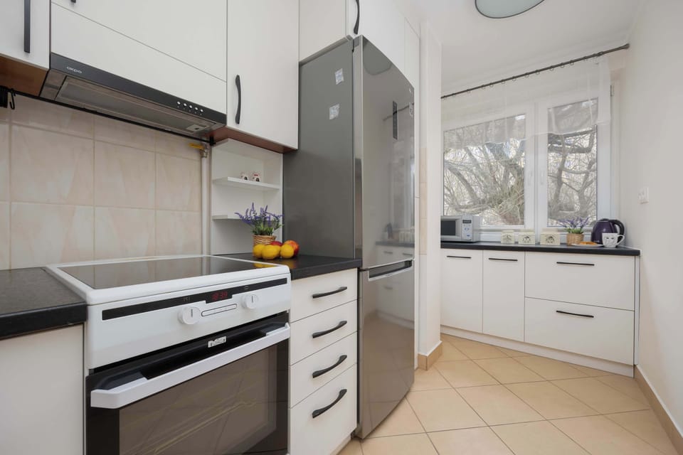 A wider perspective of the kitchen, featuring white cabinetry, a stove, and a refrigerator, keeping the space neat and practical.