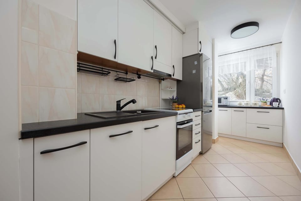 A modern kitchen with white cabinets, black countertops, and a stove, designed with functionality and aesthetics in mind.
