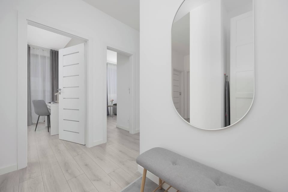 A minimalist hallway leading into different rooms. The light-colored walls and flooring add brightness and a sense of space.