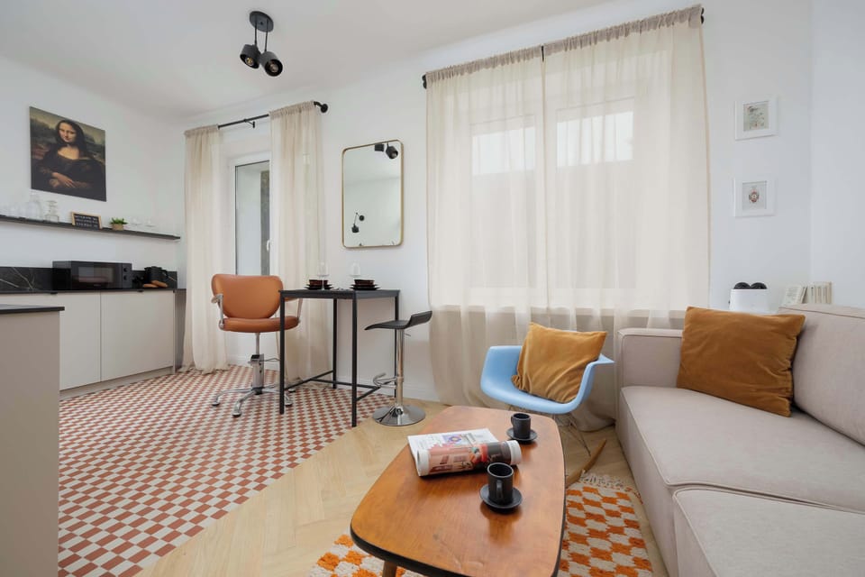 An open-plan living and dining area with high stools at a bar-style table and a comfortable sofa near the window.