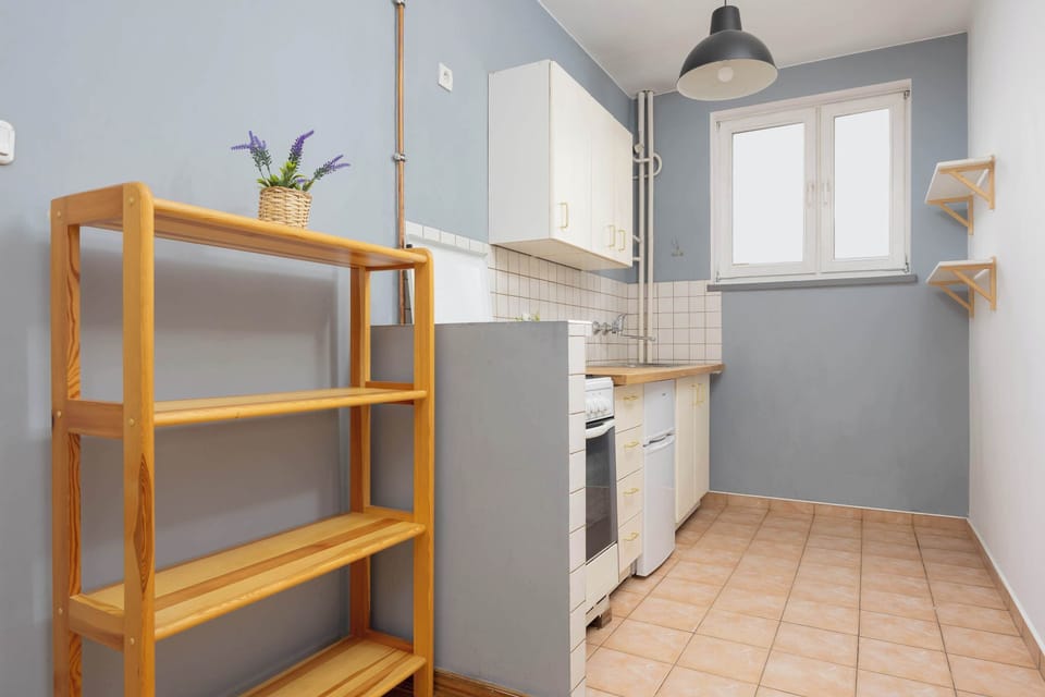 A kitchenette with white cabinets and a tiled backsplash. A wooden countertop contrasts with the modern design.
