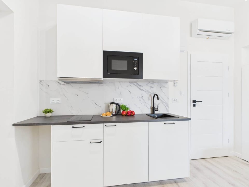 Another angle of the kitchen showing the entrance door and sleek cabinetry. The design emphasizes practicality and style.