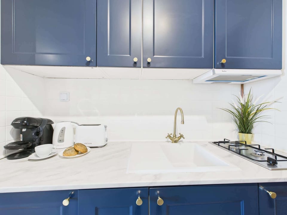 A compact kitchen setup with white tiled backsplash and blue cabinets.