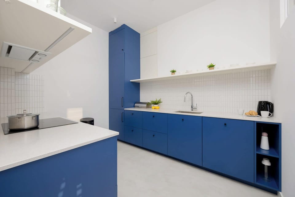 Modern kitchen featuring bold blue cabinetry, white tile backsplash, and open shelving for a functional and aesthetic appeal.
