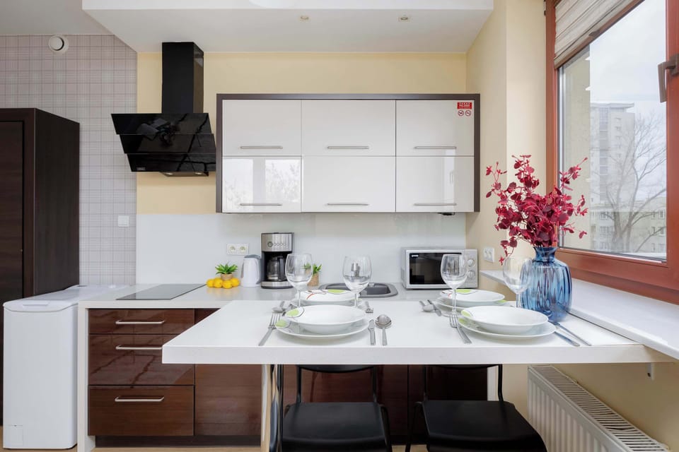 An open-concept space with a dining area and a modern kitchen in the background. The table is set with plates, glasses, and decorative flowers.