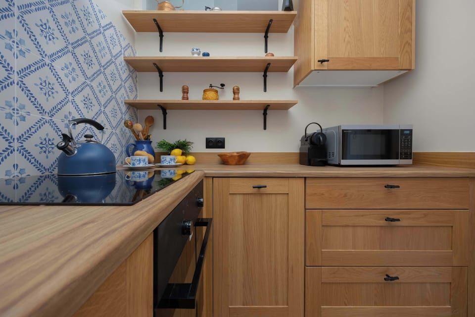 A close-up of the kitchen showing the microwave, open shelving with decor items, and wooden cabinets.