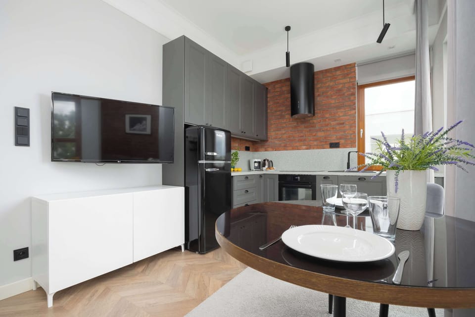 A clean and sleek kitchen design with white walls, black appliances, and a small round table set near the cooking area.