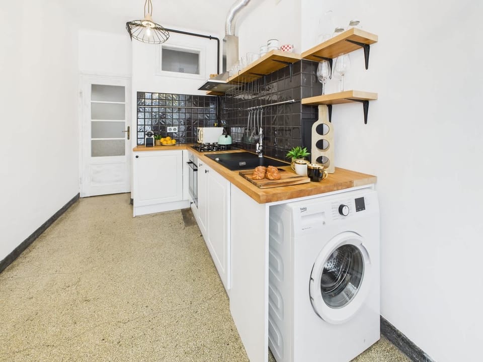 Functional and fully equipped kitchen with built-in appliances, open shelving, and a washing machine.