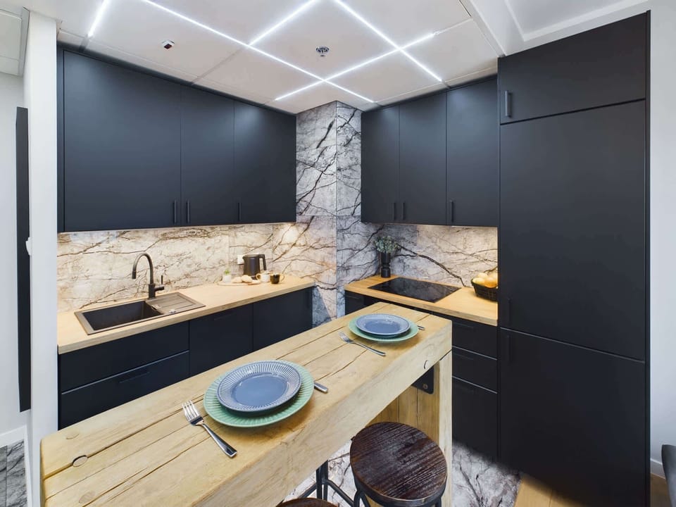 Modern kitchen with a marble island, black cabinetry, and high-end appliances.