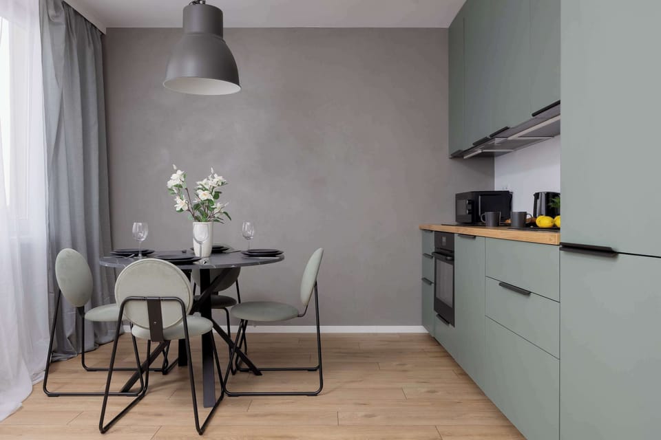 Dining area with round table and four chairs and kitchenette - a functional and elegant solution for guests.