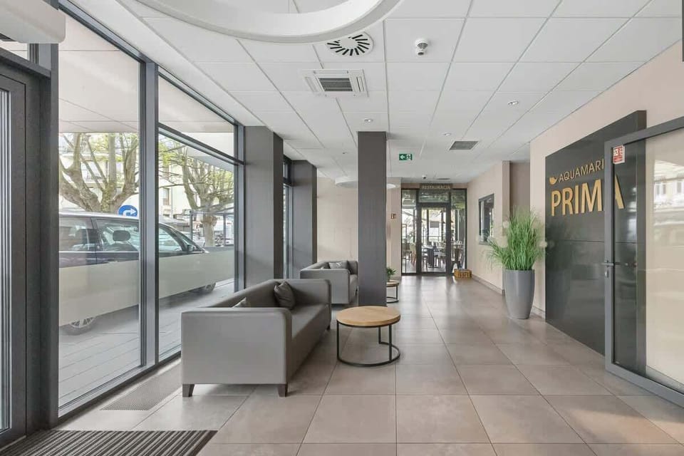A modern apartment building lobby with natural light, plants, and comfortable seating. A welcoming entrance to the residence.