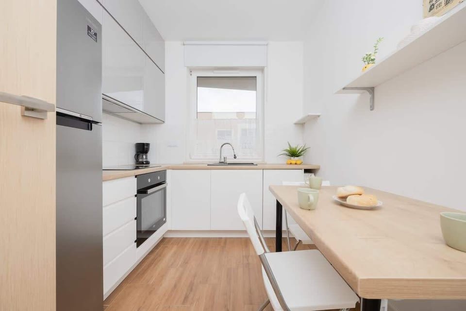 A compact kitchen with white cabinets and wooden countertops, equipped with an oven and stove. A small dining area is integrated into the layout.