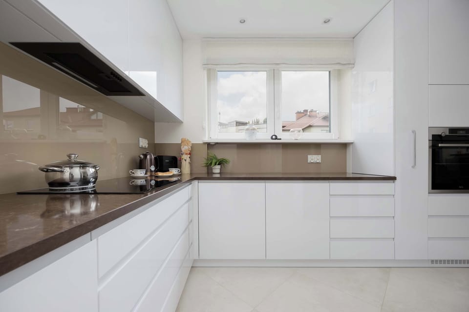 A modern kitchen in white and beige offers full freedom for meal preparation.