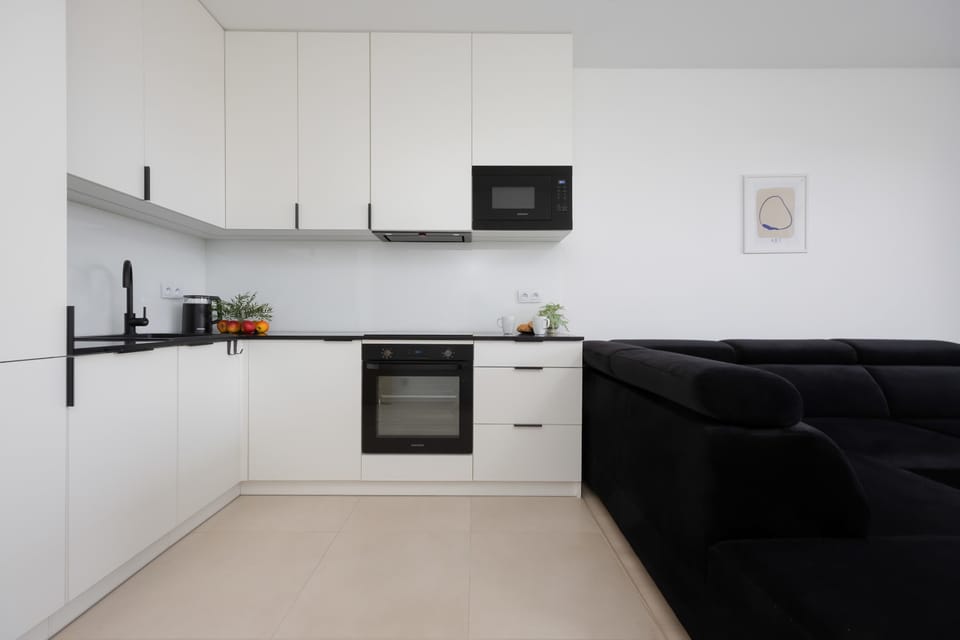 A sleek kitchen corner featuring white cabinetry, modern appliances, and minimalist decor.

