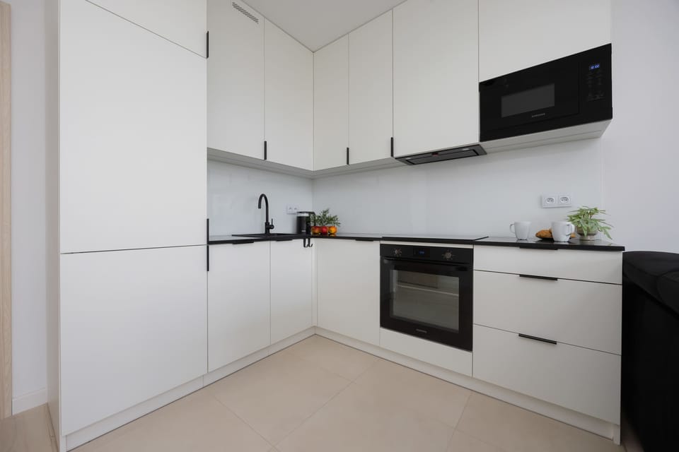 A contemporary kitchen with handleless cabinets, built-in appliances, and a soft neutral color scheme.

