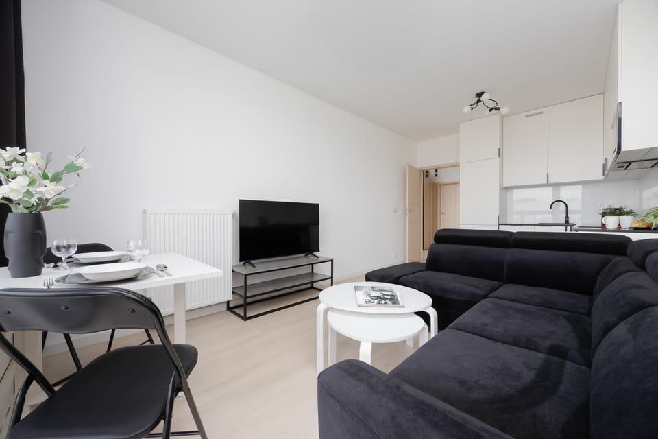 A modern sitting area with two dark sofas facing a flat-screen TV, next to a small circular coffee table.