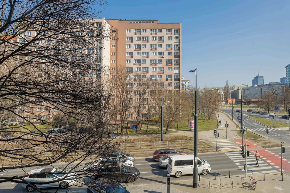 A view from the apartment window showing a cityscape with parked cars and residential buildings.