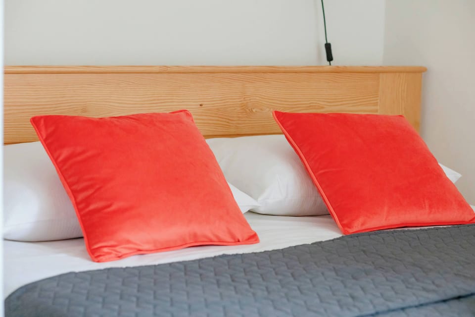 The bed with soft, vibrant pillows adds a cozy touch to the bedroom.