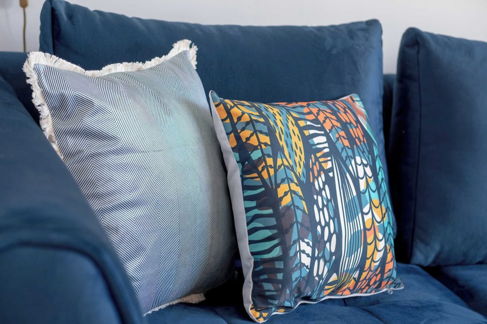 A close-up of a blue sofa with decorative pillows in geometric patterns, adding warmth and comfort.