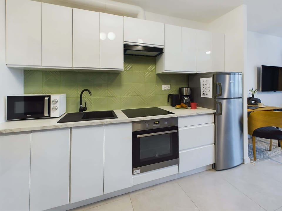 White and functional kitchenette with kettle, fridge, microwave and transfer coffee maker.