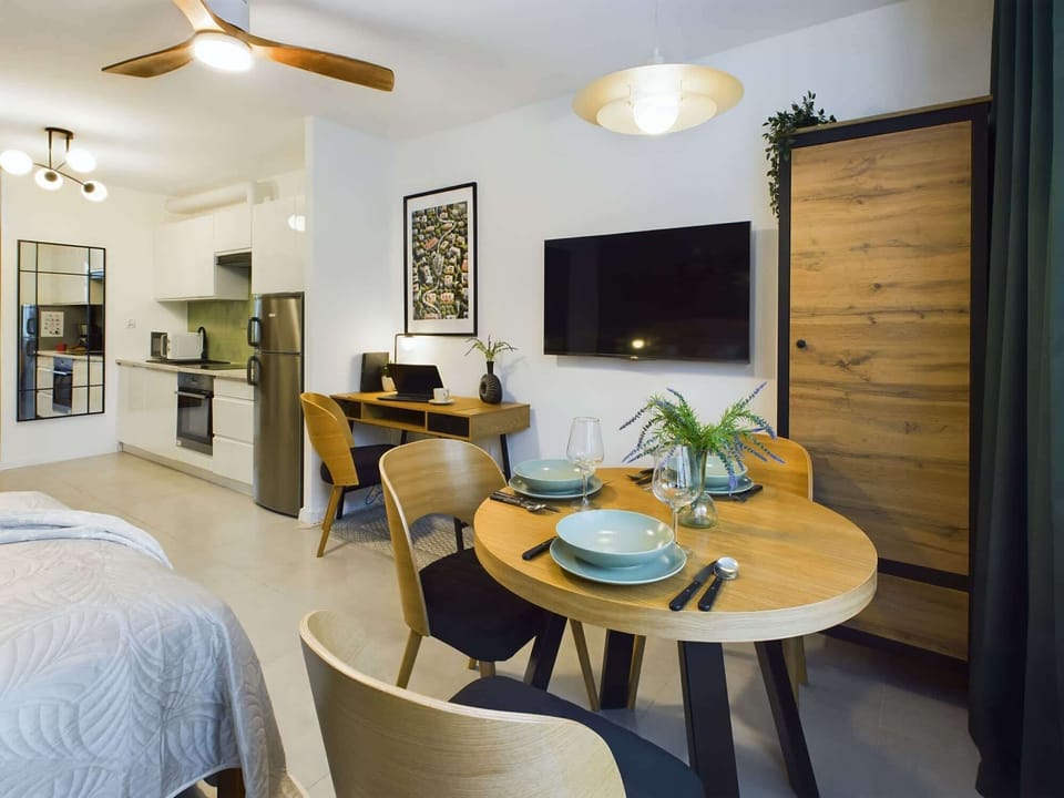 Comfortable and functional living area with dining table, wardrobe, chairs, desk, mirror, wardrobe and double bed.