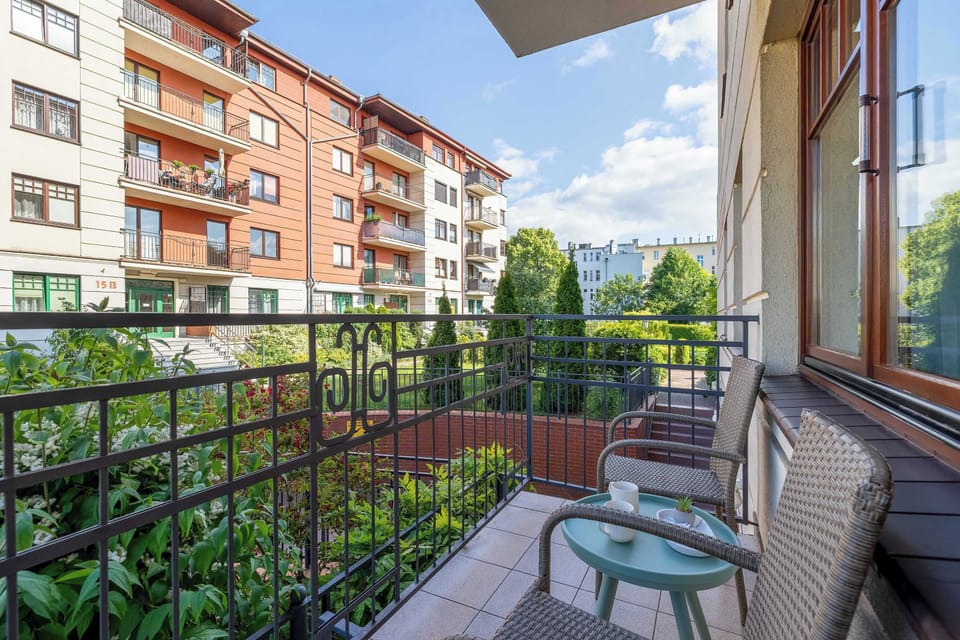 Balcony view with a small table and chairs, overlooking an apartment complex.
