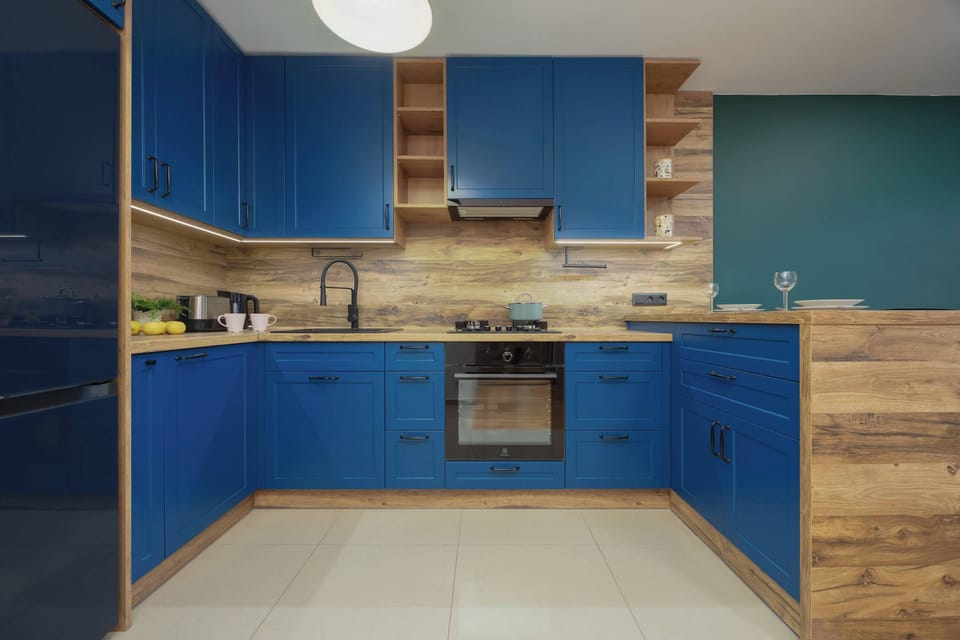 A modern kitchen with blue cabinets and wooden countertops, creating a vibrant contrast. The space is well-organized with an open feel.