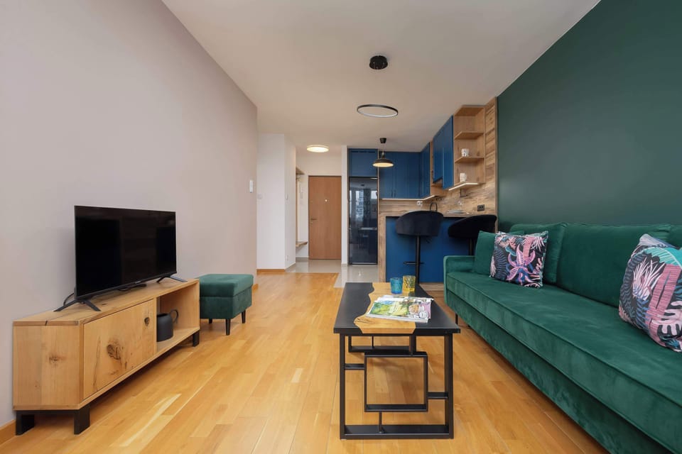 A bright living room featuring a green sofa, a coffee table, and a relaxed atmosphere. The space feels airy and open.