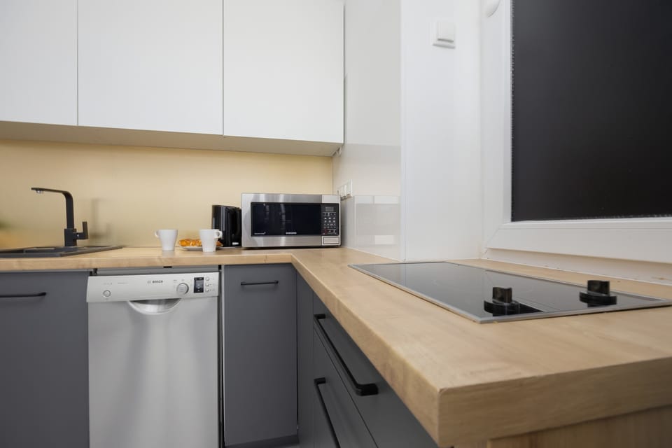 A compact kitchen space with white cabinets, wooden countertops, and modern appliances.