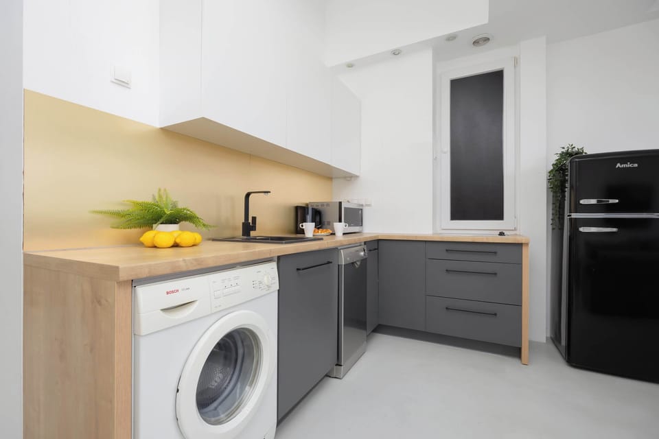 A compact kitchen space with white cabinets, wooden countertops, and modern appliances.