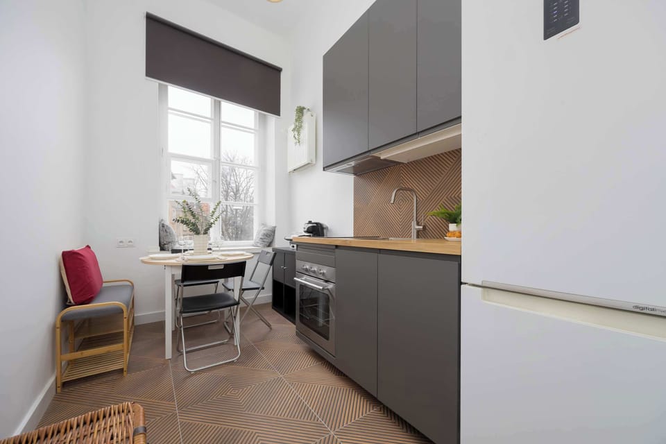 Convenient kitchen with induction cooktop, oven, electric kettle, coffee maker, refrigerator with freezer, toaster, dishwasher and dining area.