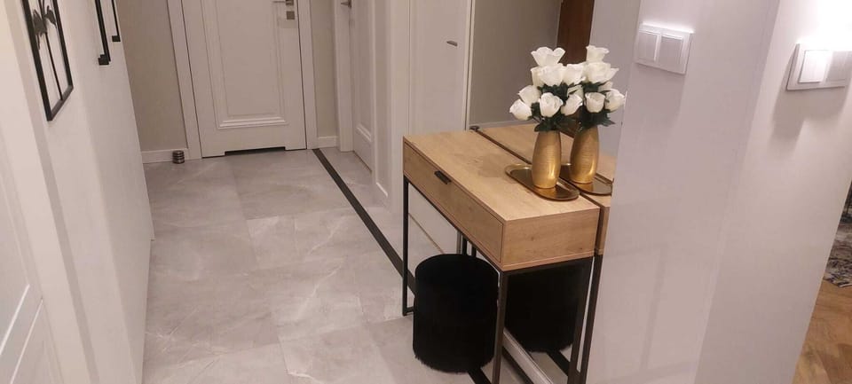 Hallway with wooden console, black stool, and flower vase creates an elegant and welcoming apartment entrance.
