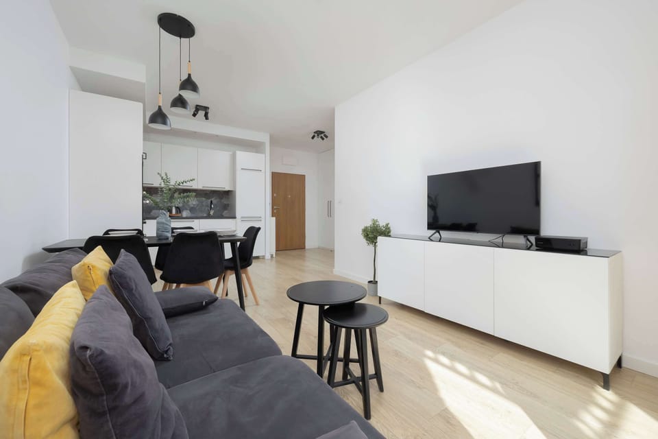 A bright and spacious living room with a comfortable gray sectional sofa, modern artwork, and a large window letting in natural light.