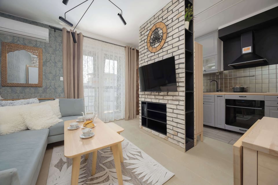 Another angle of the living area with a comfortable sofa, brick-style walls, and a mounted TV.