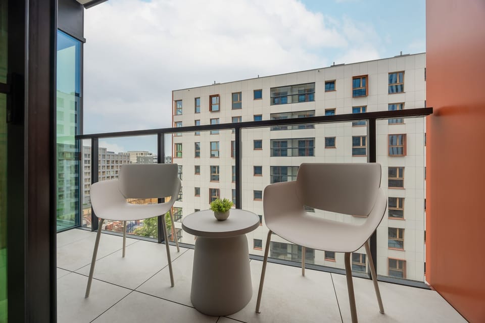 A private balcony overlooking a quiet courtyard with surrounding modern residential buildings.
