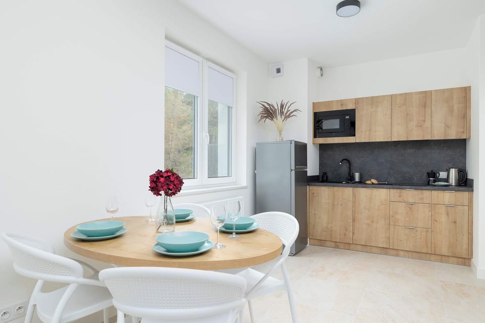 A table with a round top and white chairs connects the living room to the kitchenette. 