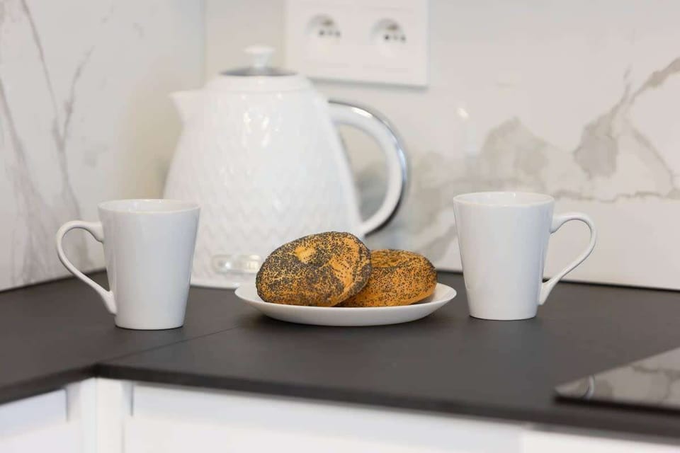 A close-up of a breakfast scene with a teapot, two mugs, and a croissant on a tray.