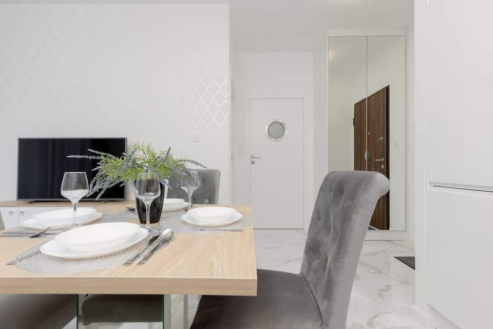 A bright dining space with a table set for meals, next to a modern kitchen.