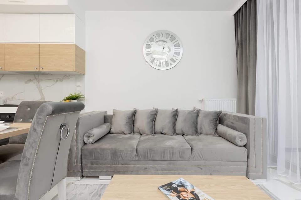 A modern open-plan living room with a gray sofa, dining table, and stylish kitchen.