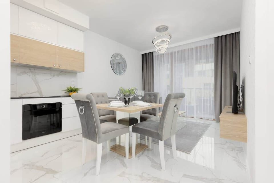 A bright dining space with a table set for meals, next to a modern kitchen.
