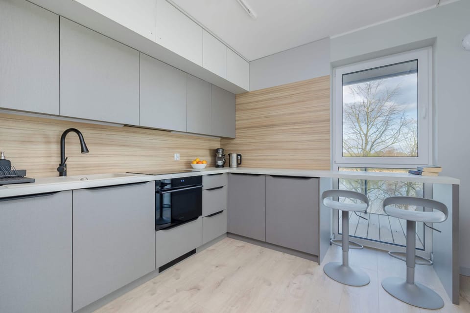 A modern kitchen with sleek wooden cabinets and a spacious countertop. Fully equipped for preparing meals.