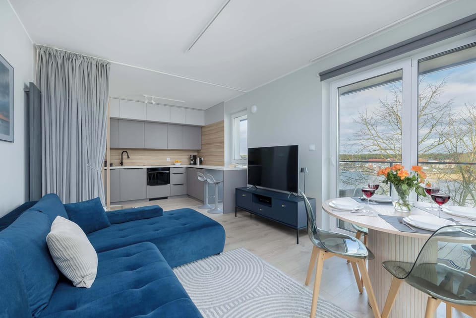 A stylish living room with a plush blue couch and floor-to-ceiling curtains. A perfect place to relax and unwind.